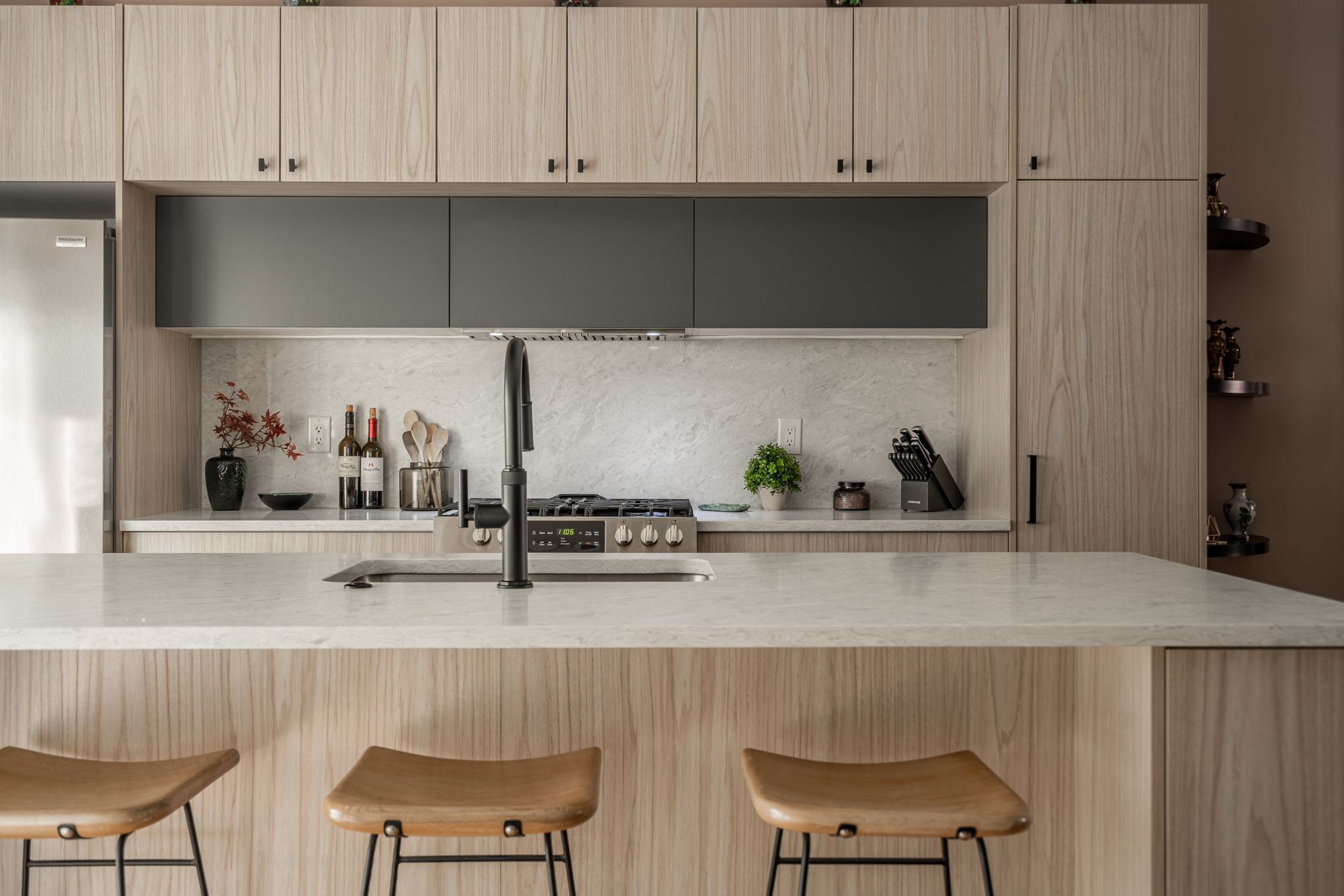 Pale oak kitchen with graphite upper cabinetry and marble backsplash by K&B Interiors